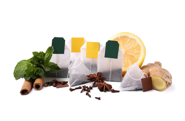 Diferentes bolsitas de té, especias y la mitad de limón sobre fondo blanco - Foto, imagen