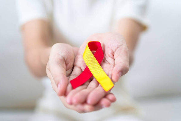Kırmızı ve sarı kurdele tutan kadın. Dünya Hepatit Günü Farkındalık Ayı, 28 Temmuz, Karaciğer kanseri, Sarılık, Siroz, Başarısızlık, Büyümüş, Hepatik Ensefalopati ve Sağlık Konsepti - Fotoğraf, Görsel