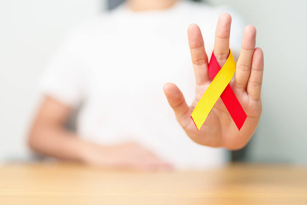 woman holding Red and Yellow ribbon. World hepatitis day awareness month, 28 July, Liver cancer, Jaundice, Cirrhosis, Failure, Enlarged, Hepatic Encephalopathy and Health concept - Photo, Image