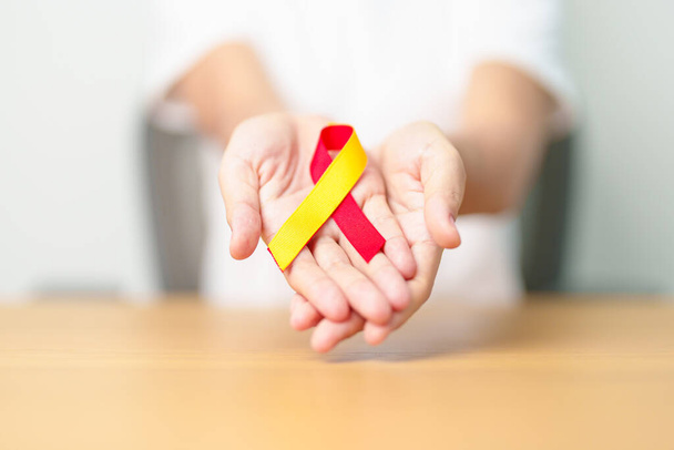 woman holding Red and Yellow ribbon. World hepatitis day awareness month, 28 July, Liver cancer, Jaundice, Cirrhosis, Failure, Enlarged, Hepatic Encephalopathy and Health concept - Photo, Image