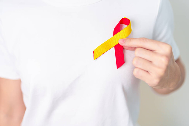 赤と黄色のリボンを持つ女性。世界肝炎の日の認識月, 28 7月,肝癌,黄疸,肝硬変,障害,拡大,肝性脳症と健康の概念 - 写真・画像