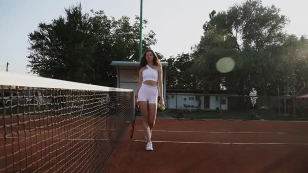 Μια νεαρή γυναίκα που παίζει τένις σε ένα πήλινο αθλητικό δικαστήριο.Η έννοια του παιχνιδιού τένις - Πλάνα, βίντεο