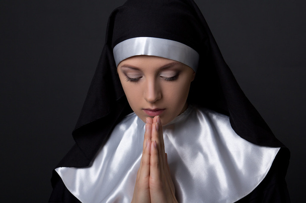 Portret van jonge mooie biddende nun over grijs - Foto, afbeelding