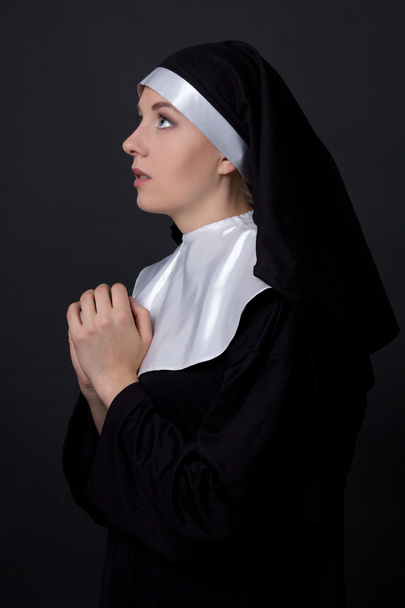 concepto de religión - monja joven orando sobre gris - Foto, imagen