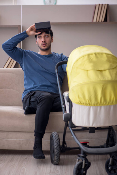 Young contractor looking after baby at home - Foto, imagen