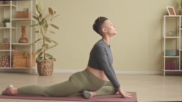 Young relaxed pregnant woman stretching on yoga mat during home practice, keeping her eyes closed and breathing deeply - Imágenes, Vídeo