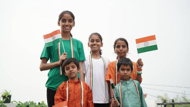 Little Indian village girls and boy proudly holds the tricolour Indian flag. Teenager holding national flag - Photo, Image