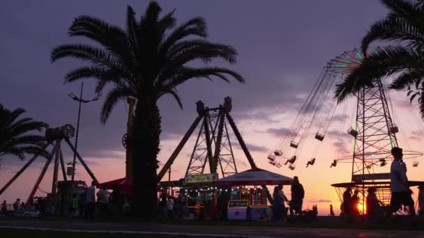 Batumi, Georgia - 3 toukokuu 2023: karuselli ratsastaa pyörii nopeasti ilmassa auringonlaskun - vintage suodatin vaikutukset - keinuvat karuselli oikeudenmukainen ratsastaa huvipuistossa hämärässä - Materiaali, video