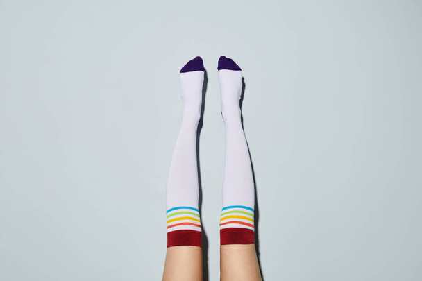 Tiro mínimo de mulher jovem usando meias de joelho alto com símbolos do arco-íris, espaço de cópia - Foto, Imagem