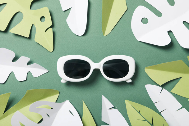 Gafas sobre fondo verde con hojas tropicales de papel - Foto, imagen