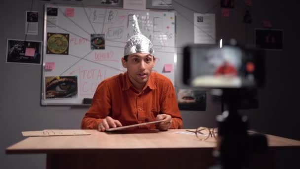 Fausses nouvelles concept. Étrange homme arabe coiffé d'un chapeau en aluminium dans son studio d'enregistrement vidéo pour son blog. Espace de copie - Séquence, vidéo