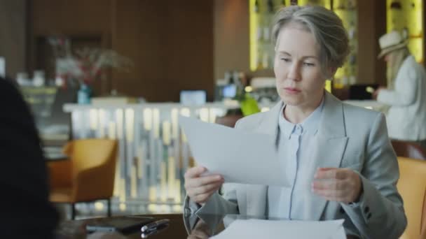 Zakenvrouw leest contract, ondertekent papieren en geeft handdruk aan partner tijdens vergadering in restaurant - Video