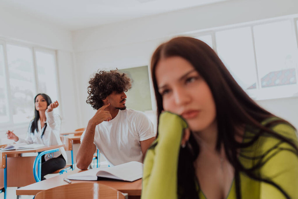A weary-looking student sitting in front of a group of diverse students in a modern classroom, capturing the blend of exhaustion, learning, and collaboration in their academic journey. - Foto, immagini