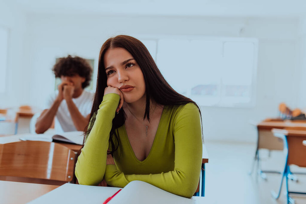 A weary-looking student sitting in front of a group of diverse students in a modern classroom, capturing the blend of exhaustion, learning, and collaboration in their academic journey. - Photo, Image