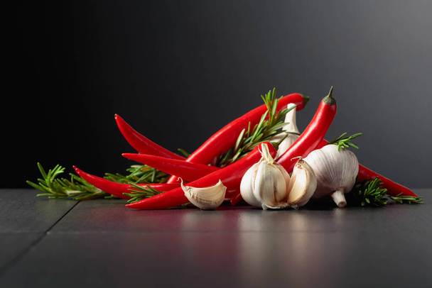 Red hot chili peppers, garlic, and rosemary on a black background.Copy space. - Fotó, kép