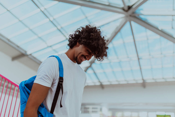 African American student with a blue backpack, sporting a modern Afro hairstyle and a wide smile, radiates enthusiasm and represents the vibrant spirit of a modern university, embodying ambition - Фото, зображення