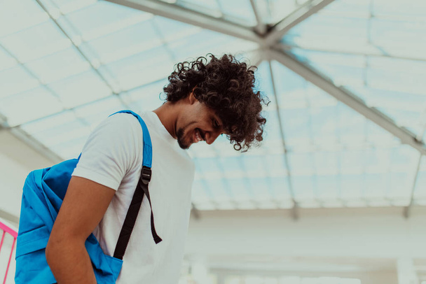 African American student with a blue backpack, sporting a modern Afro hairstyle and a wide smile, radiates enthusiasm and represents the vibrant spirit of a modern university, embodying ambition - Фото, изображение