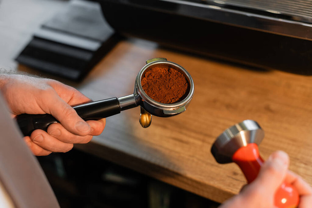 bijgesneden weergave van barista in schort houder met koffie en pers in coffeeshop - Foto, afbeelding