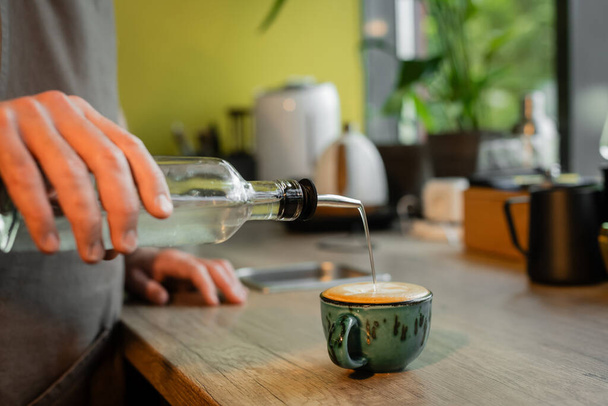 levágott kilátás barista öntés szirup csésze cappuccino a munkaasztalon kávézóban - Fotó, kép