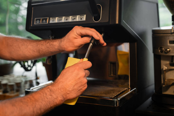 καλλιεργημένη άποψη του barista με κουρέλι καθαρισμού ακροφύσιο μηχανή καφέ, ενώ εργάζονται σε καφετέρια - Φωτογραφία, εικόνα