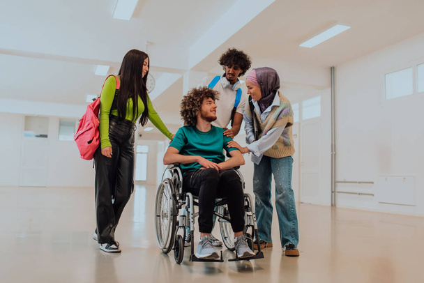 Em uma universidade moderna, um grupo diversificado de estudantes, incluindo um estudante afro-americano e uma mulher vestindo hijab, caminham juntos no corredor, acompanhados por seu colega de cadeira de rodas. - Foto, Imagem