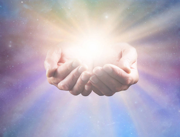 Verbind je met Goddelijke Intelligentie en Al Dat Is - volwassen mannelijke genezers bezetten handen met helder helend sterrenlicht dat naar buiten straalt tegen een hemelse achtergrond ideaal voor een spiritueel holistisch helend thema - Foto, afbeelding