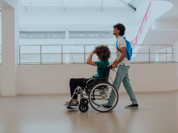 Afroamerikanischer Student schiebt seine Freunde im Rollstuhl durch eine moderne Schule und demonstriert Inklusion, Barrierefreiheit und die Kraft der Freundschaft. Hilfe für Menschen mit Behinderungen. - Foto, Bild
