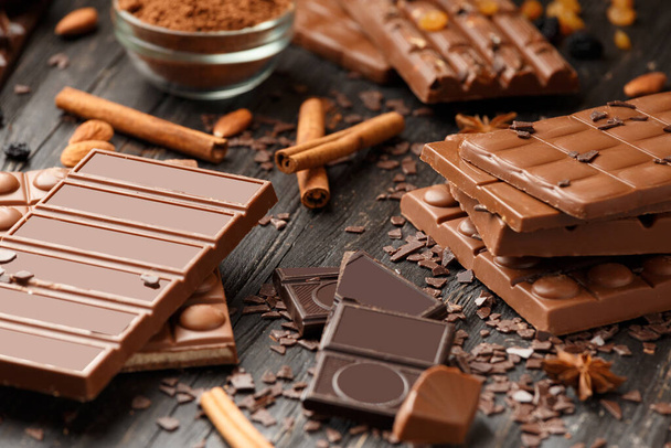 Whole and broken chocolate, chocolate bars, candies, chocolate chips on a dark wooden background - Photo, Image