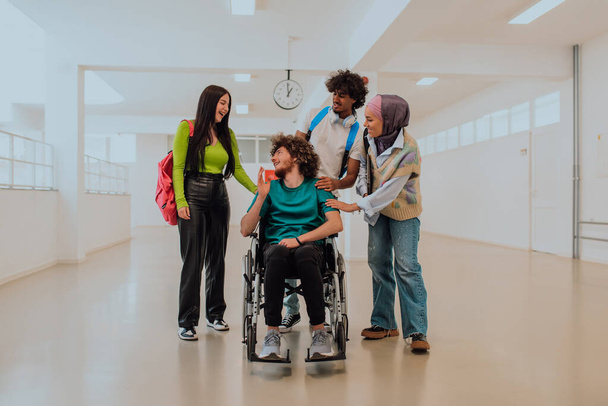 En una universidad moderna, un grupo diverso de estudiantes, incluyendo un estudiante afroamericano y una mujer que usa hiyab, caminan juntos en el pasillo, acompañados por su colega en silla de ruedas. - Foto, imagen