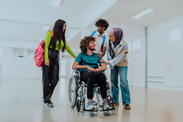 En una universidad moderna, un grupo diverso de estudiantes, incluyendo un estudiante afroamericano y una mujer que usa hiyab, caminan juntos en el pasillo, acompañados por su colega en silla de ruedas. - Foto, imagen