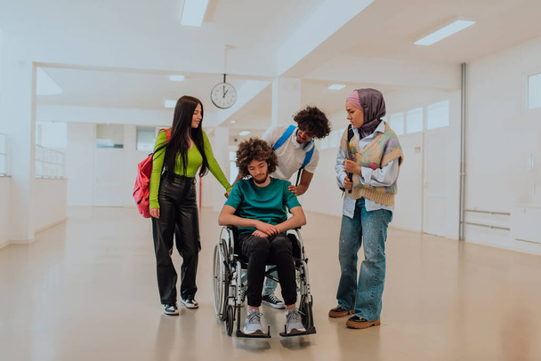 Dans une université moderne, un groupe diversifié d'étudiants, y compris un étudiant afro-américain et une femme portant un hijab, marchent ensemble dans le couloir, accompagnés de leur collègue en fauteuil roulant. - Photo, image