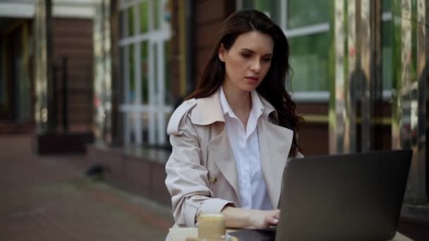 Μεσήλικη γυναίκα εργάζεται σε ένα καφέ σε ένα φορητό υπολογιστή, ενώ είναι σε διακοπές. επείγουσα δουλειά, ενώ περιμένουν για μεσημεριανό γεύμα και καφέ. Αγχωτική απομακρυσμένη δουλειά. Υψηλής ποιότητας 4k πλάνα - Πλάνα, βίντεο