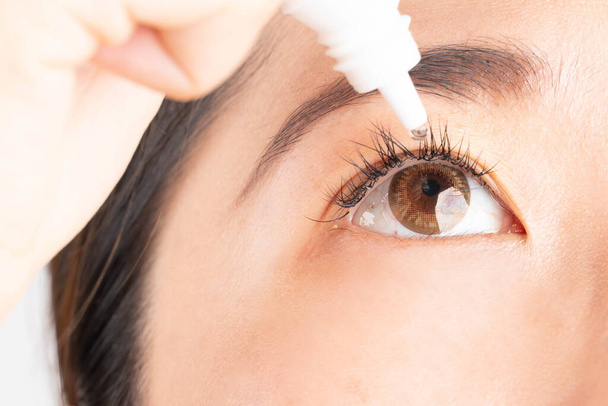 Женщина применяет искусственную слезоточивую каплю для облегчения сухих глаз, раздраженного глаза, конъюнктивита или оптических симптомов. Закрыть. - Фото, изображение