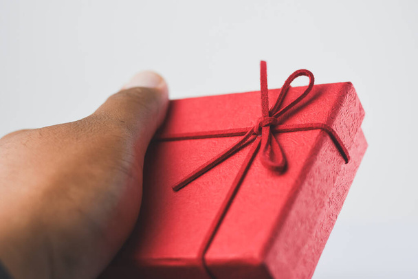 Männliche Hand hält eine rote Geschenkbox auf weißem Hintergrund - Foto, Bild