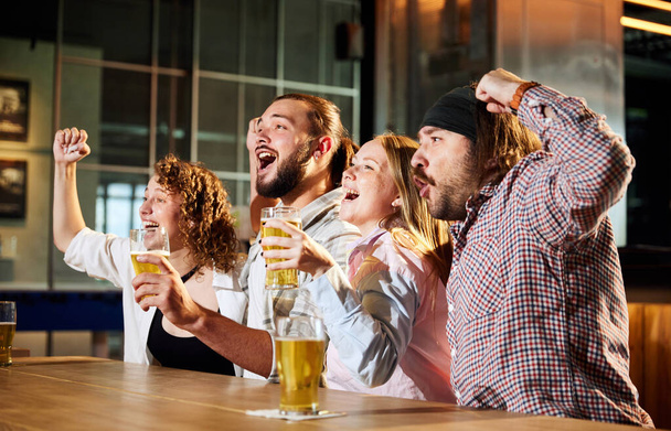 Excited young men and women, friends meeting at pub, bar, watching online sport match translation and cheering up favourite team. Concept of sport competition, hobby, lifestyle, human emotions, fun - Fotoğraf, Görsel