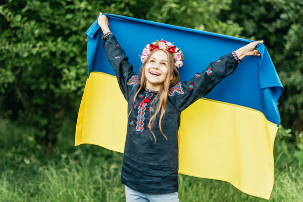 Ukraines Independence Flag Day. Constitution day. Ukrainian child girl in embroidered shirt vyshyvanka with yellow and blue flag of Ukraine in field. flag symbols of Ukraine. Kyiv, Kiev day - Photo, Image
