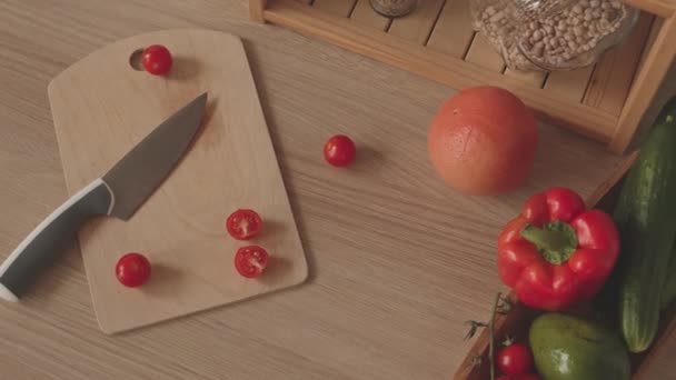 Top view of wooden cutting board and fresh fruits and vegetables on kitchen table - Video