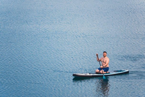 man on paddleboard in the middle of the lake copy space - Fotó, kép