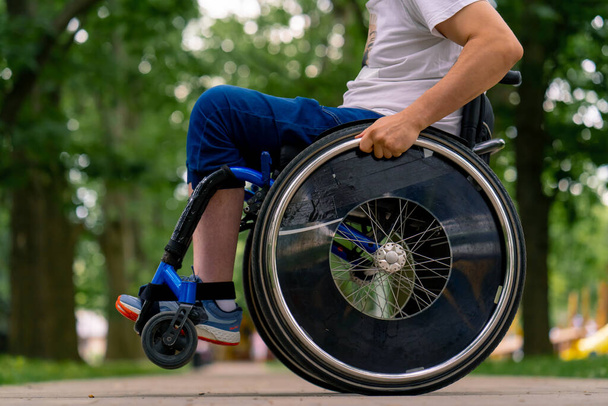 Özürlü bir adam şehir parkında ağaçlara karşı tekerlekli sandalye dublörlüğü yapar. - Fotoğraf, Görsel