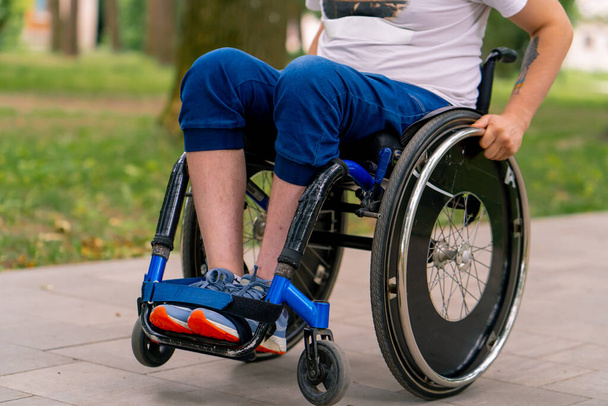 Inclusividad Un hombre con discapacidad hace acrobacias en silla de ruedas en un parque de la ciudad contra el telón de fondo de los árboles - Foto, imagen