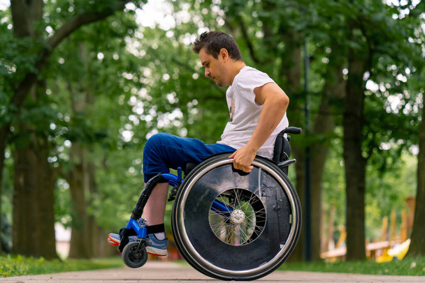 Inkluzivita Muž se zdravotním postižením dělá invalidní vozík kaskadérské kousky v městském parku na pozadí stromů - Fotografie, Obrázek