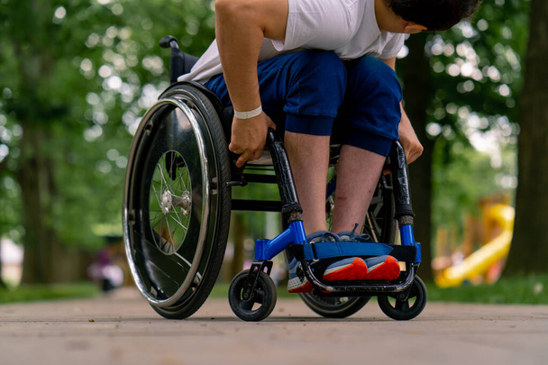 包括性 障害のある男性は,木の背景に対して市の公園に車椅子が立っています - 写真・画像