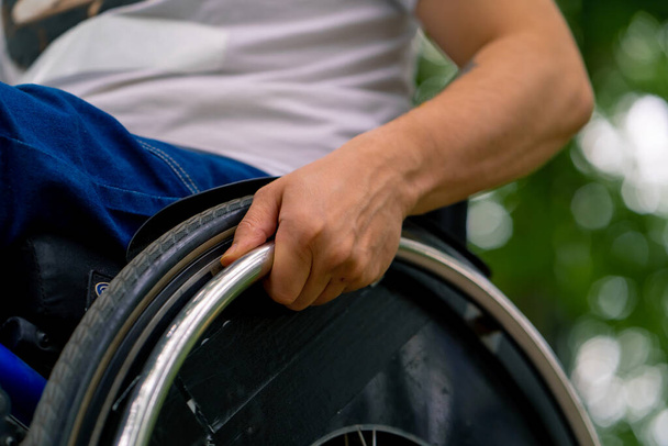 Inclusividad Primer plano de la mano de un hombre con discapacidad que monta una silla de ruedas en el parque de la ciudad - Foto, Imagen