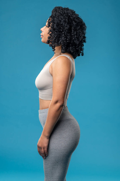 Sporty woman. Curly-haired woman standing on a blue background - Foto, Imagem