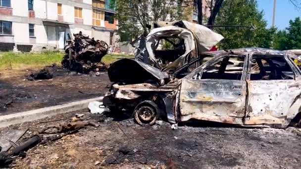 Burned-out cars at the site of the missile strike. In the background are residential buildings with broken windows. Russian-Ukrainian War 2022-2023. Missile attack on residential buildings in - Video, Çekim