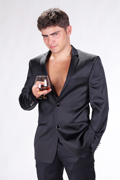 Business man in black suit holding glass of cognac isolated on w - Φωτογραφία, εικόνα