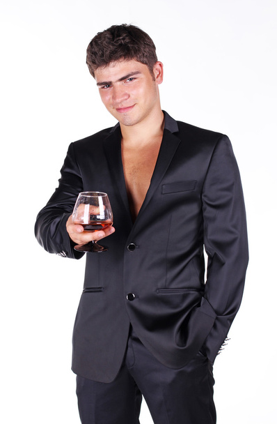 Business man in black suit holding glass of cognac isolated on w - Фото, изображение