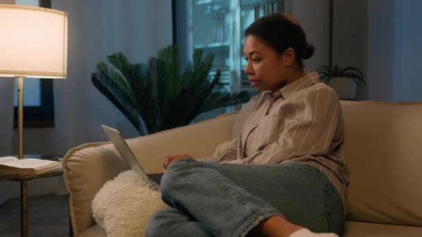 Ideges stresszes nő afro-amerikai lány lakástulajdonos zavaros megdöbbent hölgy nem online vizsga laptop negatív eredmény rossz hír ideges nő kanapén számítógépes probléma hiba sokk este otthon - Felvétel, videó