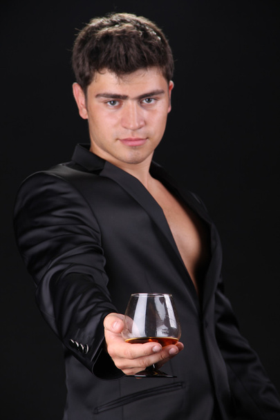 Man present glass of cognac on dark background, business - Zdjęcie, obraz