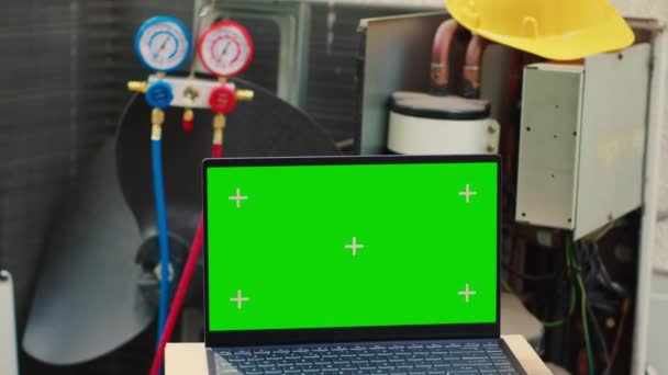 Chroma key laptop in front of unfunctional opened external air conditioner. Mock up green screen gadget display next to broken outdoor condenser in need of professional checkup - Footage, Video